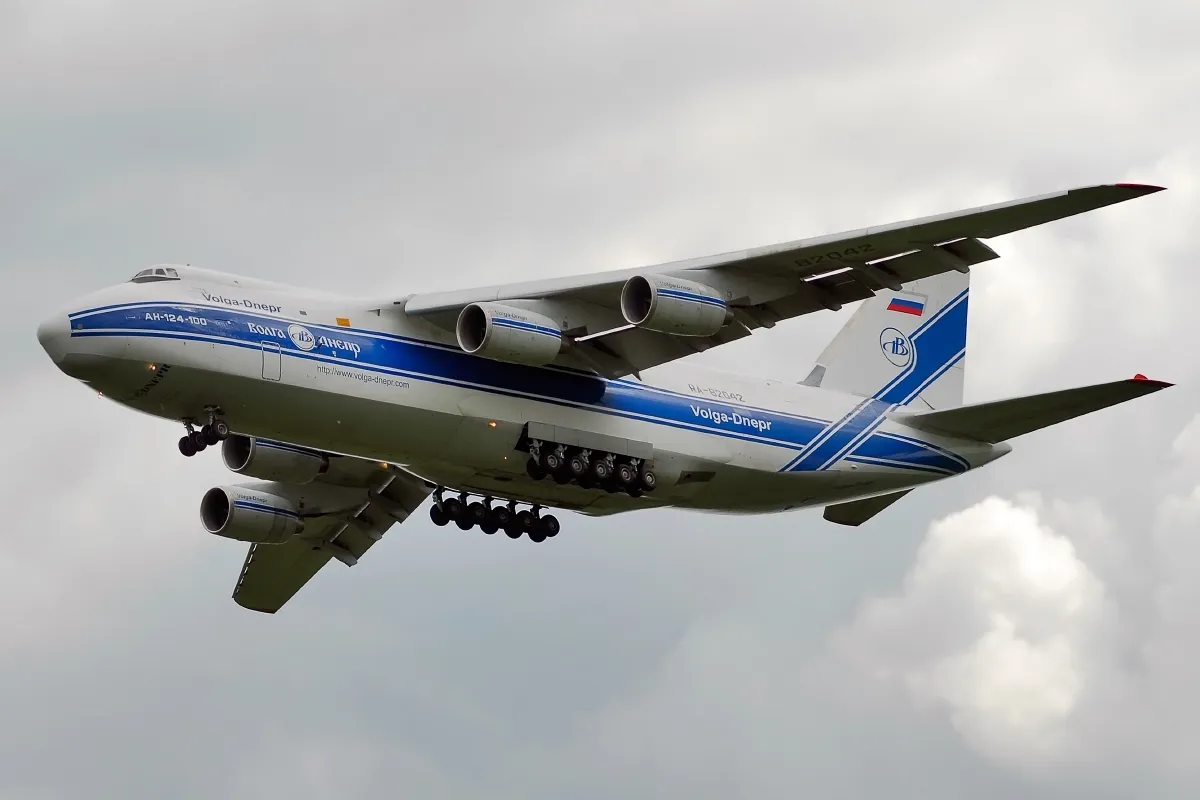 An Antonov An-124 Ruslan cargo plane on approach to land, landing gear down, against a clear sky.