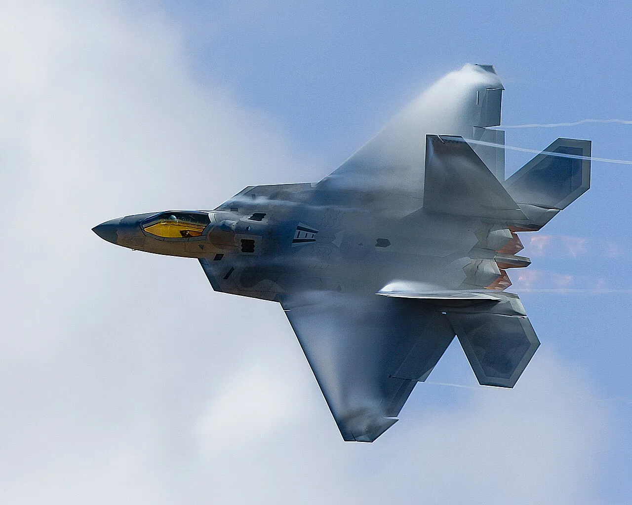 A U.S. Air Force F-22 Raptor banking sharply during a high-speed pass at an air show.