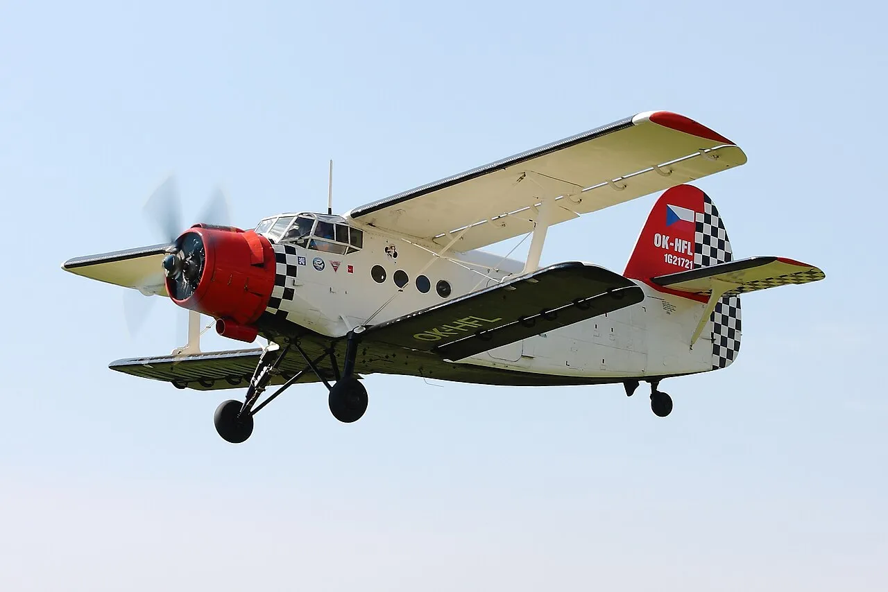 An Antonov An-2 biplane, registration OK-HFL, parked on an airfield apron seen from the rear.