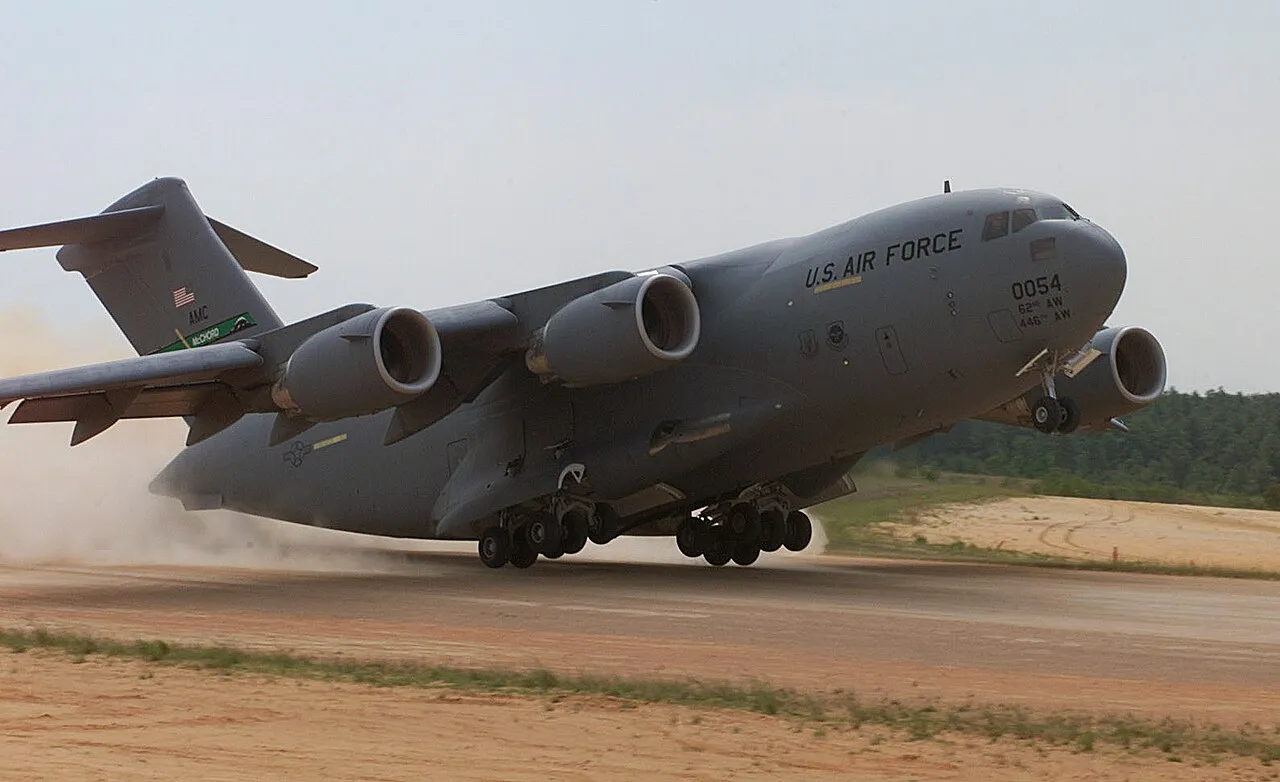 A C-17 Globemaster III of the 446th Airlift Wing performing an assault landing on an unpaved runway during an exercise.