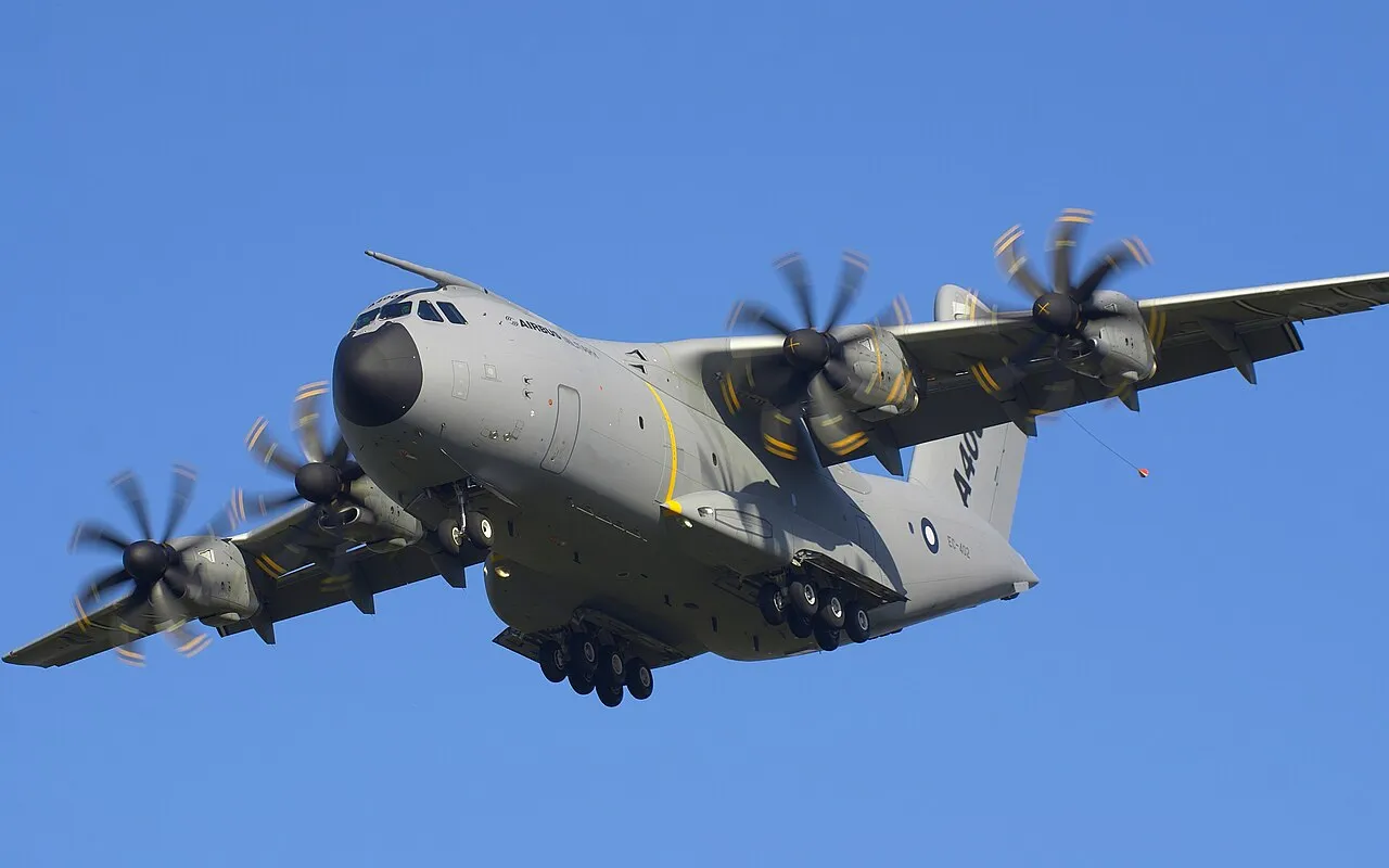 An Airbus A400M Atlas military transport aircraft on final approach, its high-mounted wing and four turboprop engines visible.