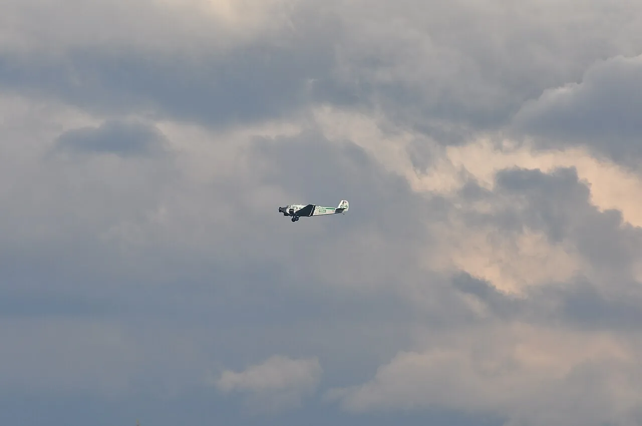 A three-engined Junkers Ju 52 in flight against a cloudy sky.