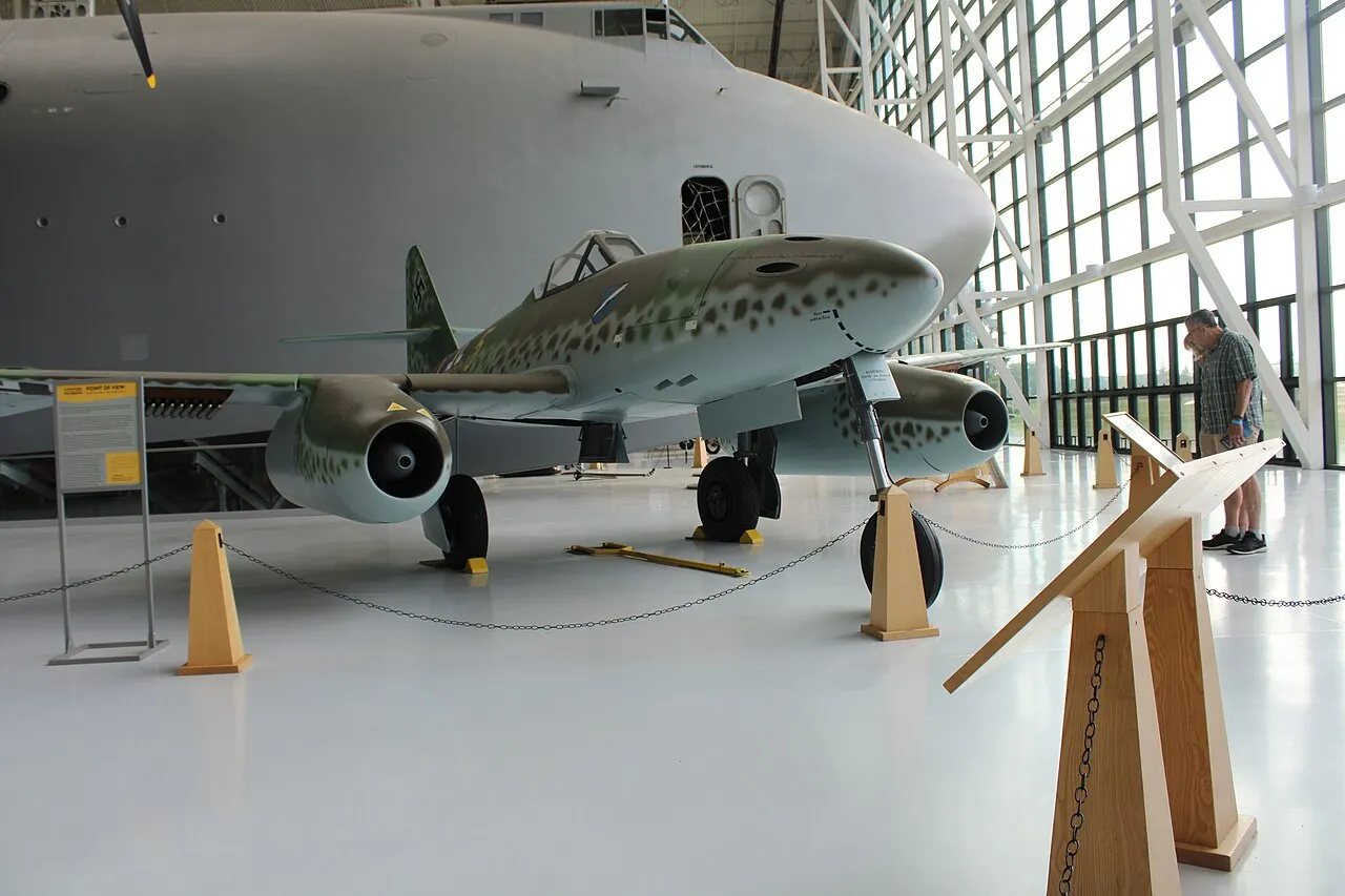 A preserved Messerschmitt Me 262 jet fighter on static display, its twin underslung engine nacelles and swept wing visible.