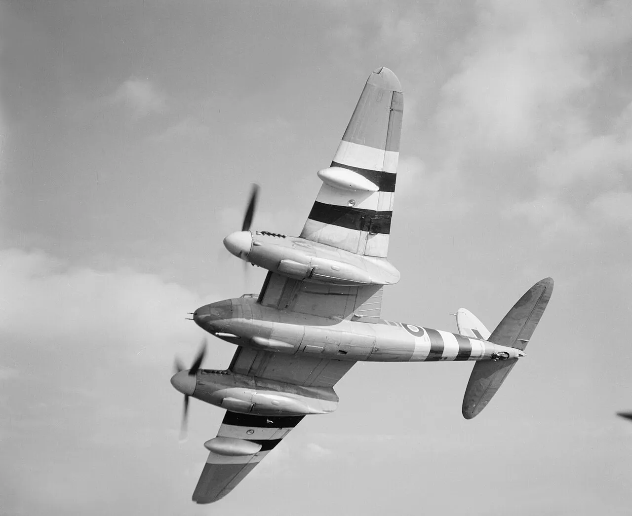 A De Havilland Mosquito FB Mark XVIII banking in flight, showing the 57mm Molins gun mounted under its nose.