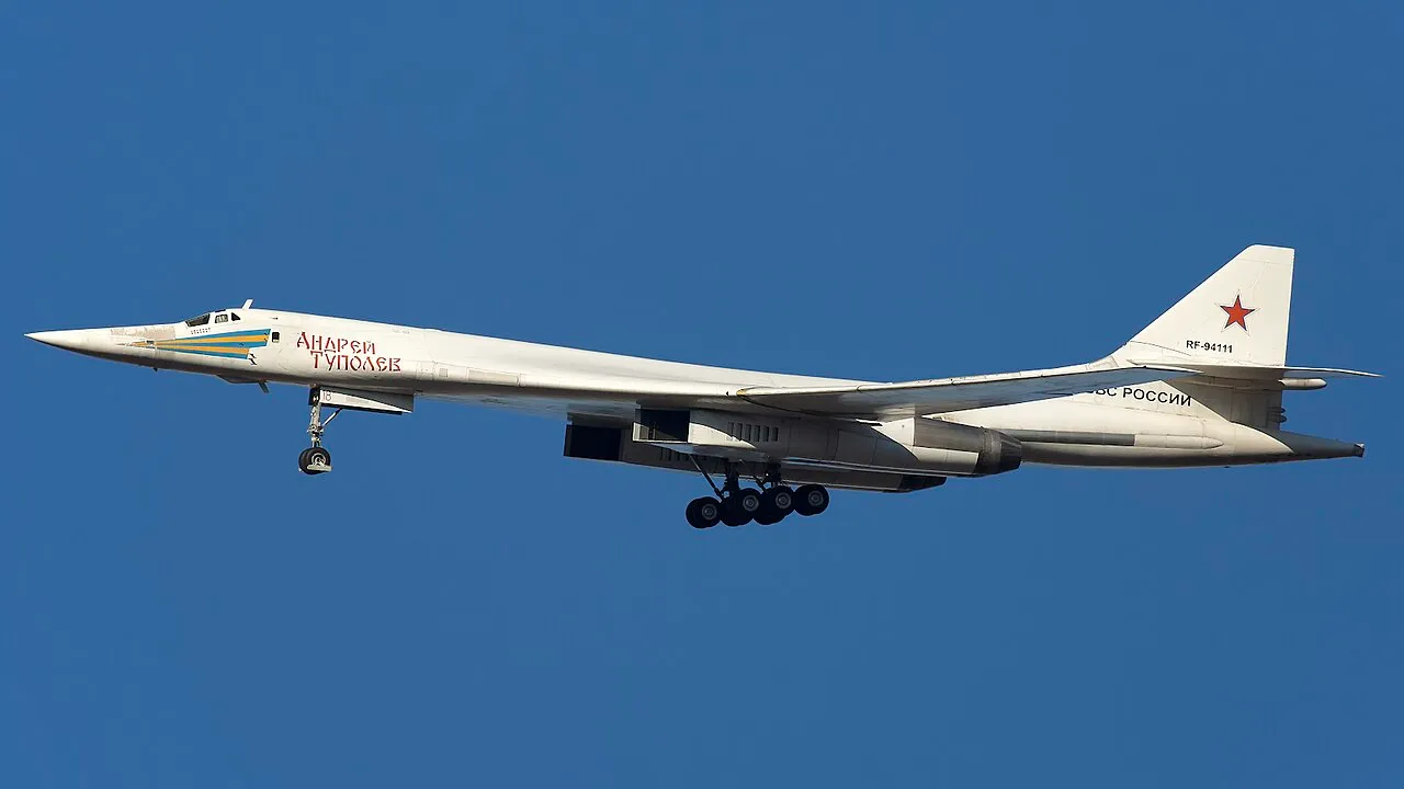 A Tupolev Tu-160 supersonic strategic bomber in flight, its swept wings extended and four engine nacelles visible beneath the fuselage.