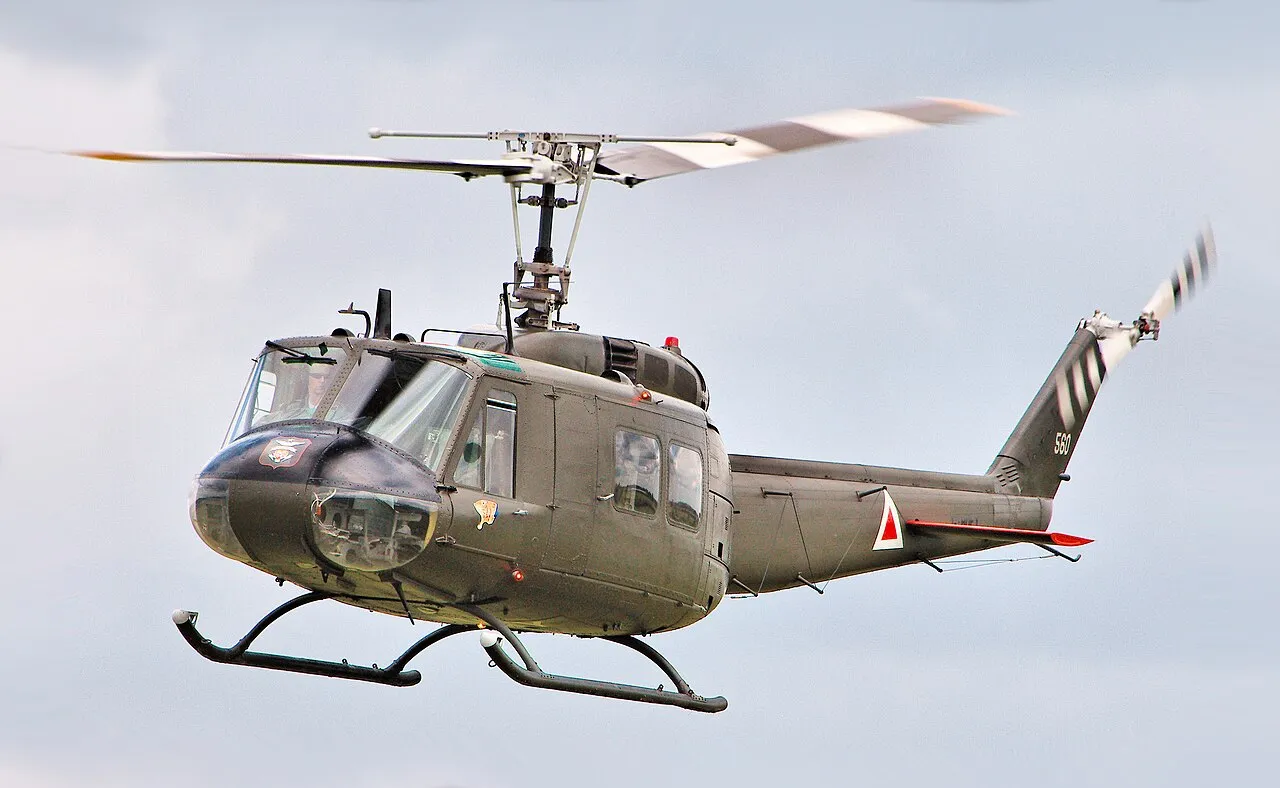 A civilian-owned Bell UH-1 Iroquois helicopter painted in Vietnam-era US Army livery, parked on an airfield.