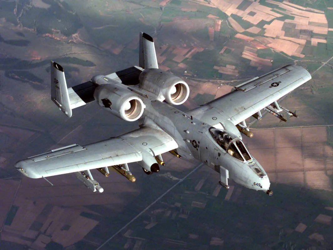 A U.S. Air Force A-10 Thunderbolt II in flight, carrying bombs and an electronic jamming pod under its wings.