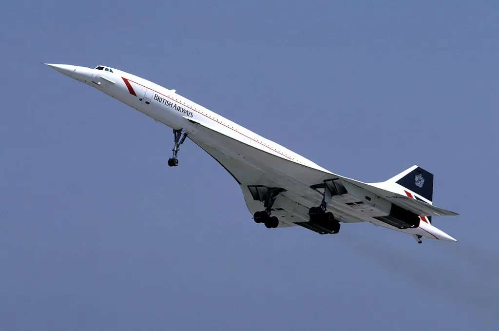 A British Airways Concorde in the Landor livery banking against a cloudy sky.